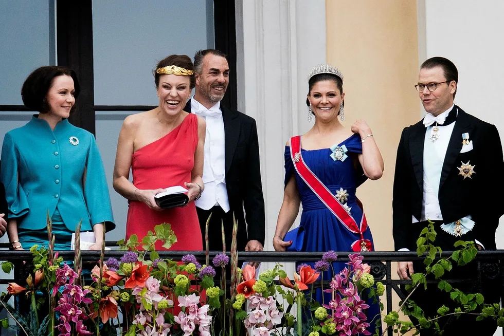Gjester hilste ned til folket fra slottsbalkongen i anledning kongeparets 80-årsfeiring denne uken. Fra venstre: Den finske førstedamen Jenni Haukio, kronprins Haakons tremenning Desirée Kogevinas med Carlos Eugster, kronprinsesse Victoria og prins Daniel av Sverige. Foto: Jon Olav Nesvold/NTB Scanpix