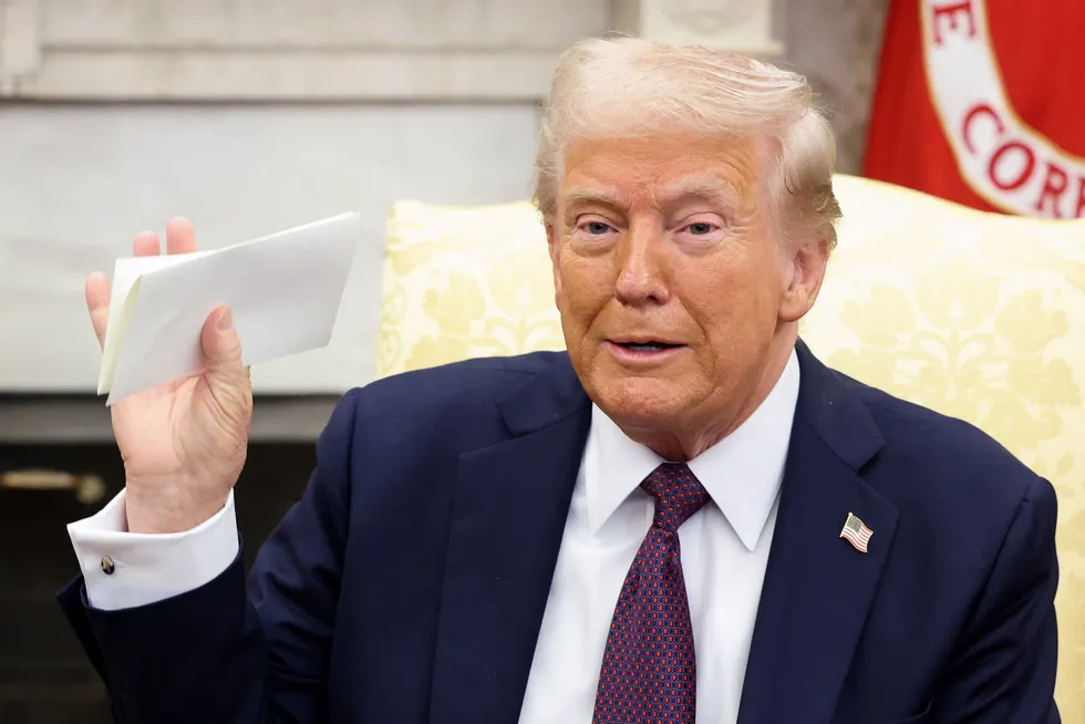 US President Donald Trump holds a letter from Britain's King Charles as he meets with British Prime Minister Keir Starmer (not pictured) in the Oval Office at the White House in Washington, DC, on Thursday, 27 February 2025.