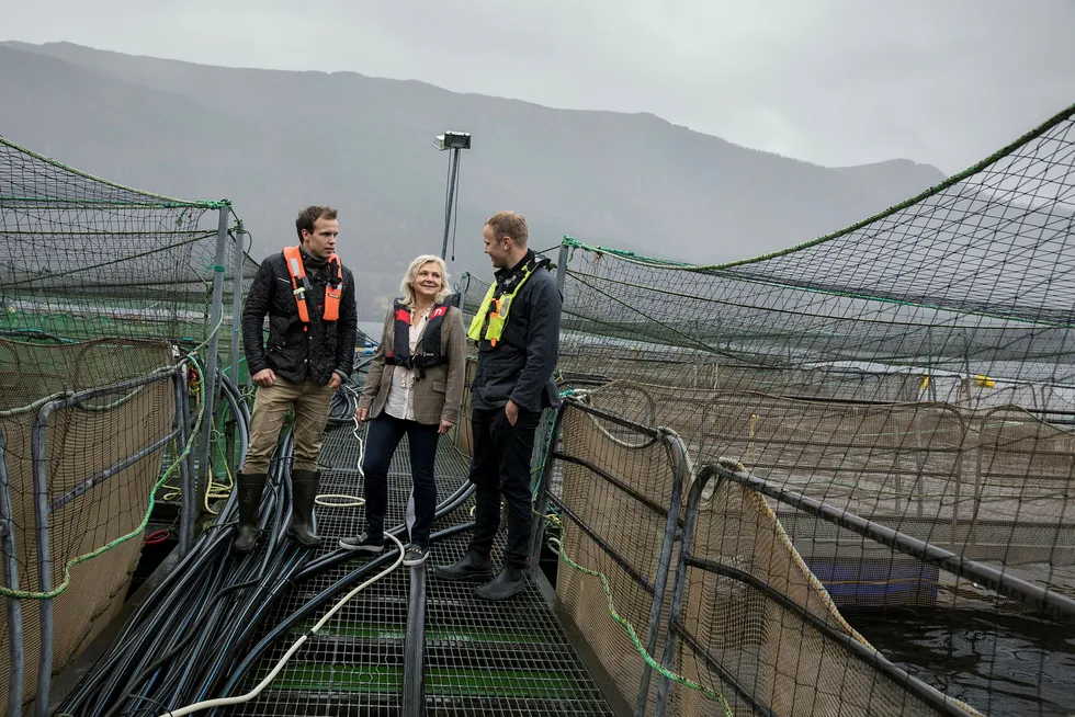 Randi Herre Eide og sønnene Erlend (til venstre) og Sondre står ute i smoltanlegget i Skogseidvatnet like ved bedriftens hovedkvarter i Fusa kommune.