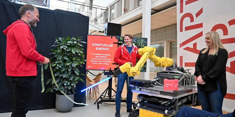 Olje- og energiminister Tina Bru har akkurat trykket på den svarte knappen på den røde terningen. Roboten fra nLink, som er et av selskapene hos Startuplab, klipper over snoren. Startuplab-sjef Per Einar Dybvik (til venstre) og Lars Flesland, som leder Startuplab Energy.