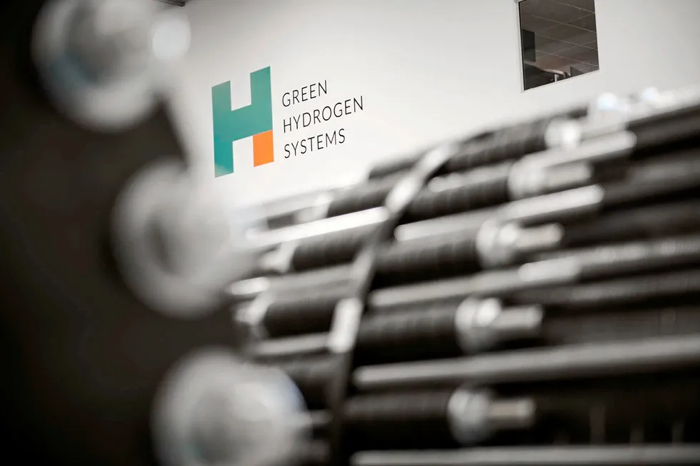 Green Hydrogen Systems' logo behind out-of-focus electrolyser stacks.