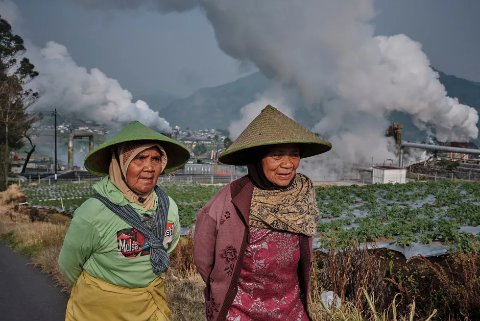 Farmers walk by as steam rises from a geothermal power plant in Dieng, Central Java, Indonesia.