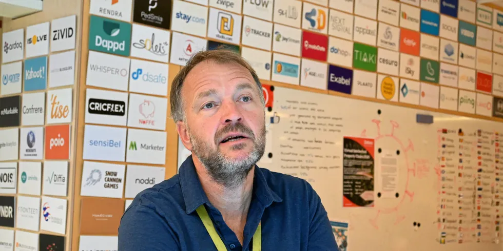 StartupLab-sjef Per Einar Dybvik foran veggen med nåværende og tidligere gründerselskaper i laben.