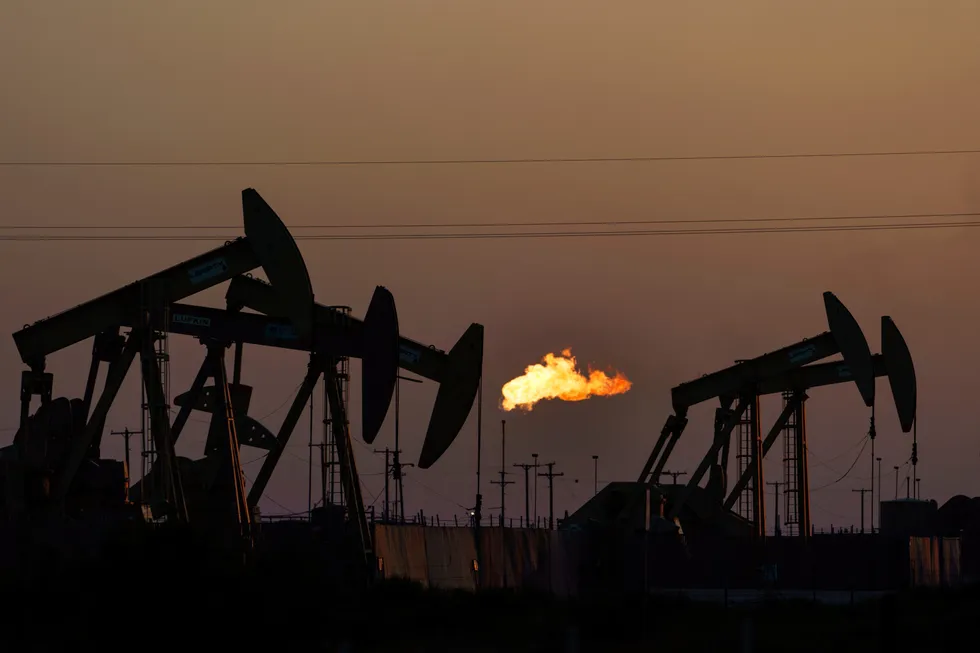 A flare burns off methane and other hydrocarbons as oil pumpjacks operate in the Permian Basin in Midland, Texas, on 12 October 2021.