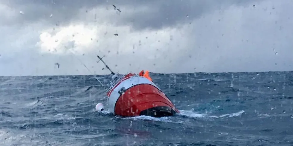 Fiskerne klamrer seg fast i fartøyet som er på vei ned. Like etter hopper de i havet og blir plukket opp av redningsskøyten «Det Norske Veritas». Foto: Redningsselskapet