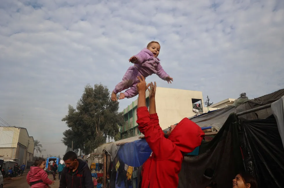 Displaced Palestinians gather outside their tents in Deir al-Balah in the central Gaza Strip on Thursday, following the announcement of a ceasefire and hostage release deal between Israel and Hamas to end the 15-month Gaza war.