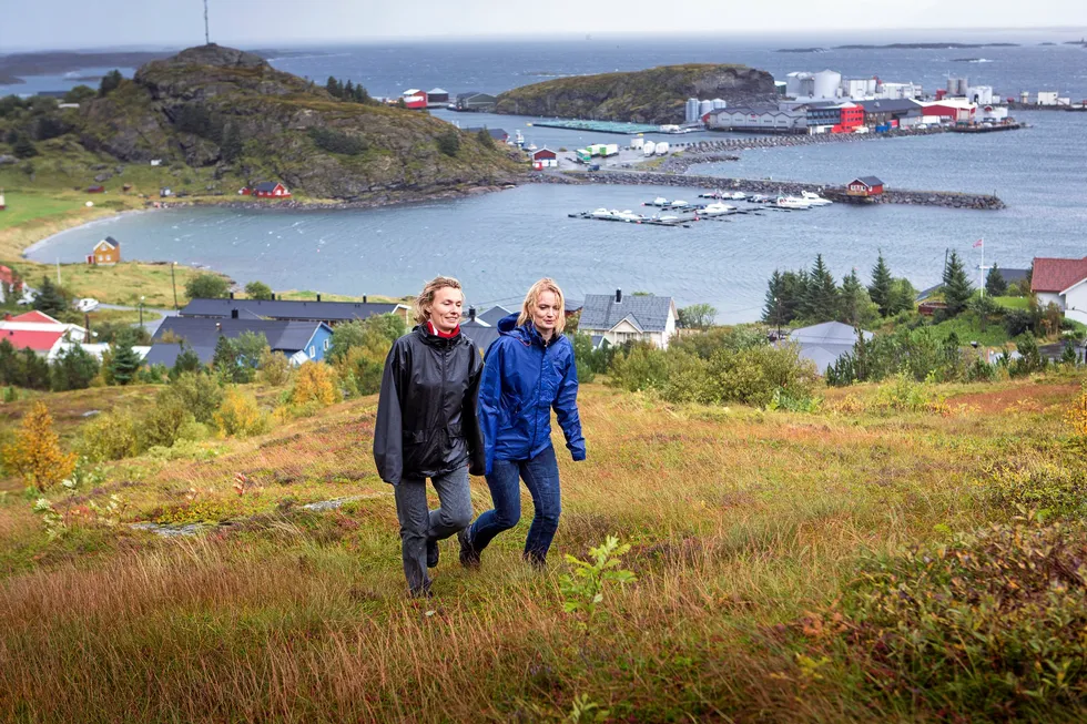 Søstrene Aino og Maria Olaisen er på tur oppover siden av Lovundfjellet. Bak ser vi Nova Sea sitt lakseslakteri. Nå selger de selskapet til Mowi, og Lovund-samfunnet står framfor et veiskille.