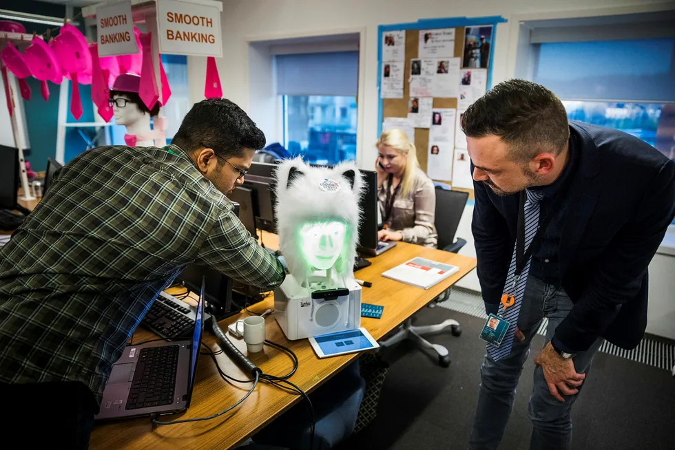 Jerin Kurian (fra venstre), Trine Lysen og Jan Thomas Lerstein jobber med å utvikle digitale kundeservice-løsninger. Roboten «Furhat» bruker menneskelig mimikk mens den prater.