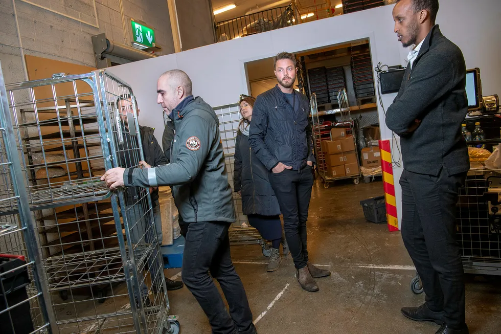 Cathrine Laksfoss fra Schibsted Distribusjon Shafi Adan og Arne Kvale i Zoopit Sjåfører Ali Goher Abbas, Naob Fissehaye pakker varer på trallen før utkjøring. Traian Marius Dinca passerer med tralle i bakgrunnen. Schibsted ruster mot Amazon og satser på logistikk. På Meny på Bryn.
