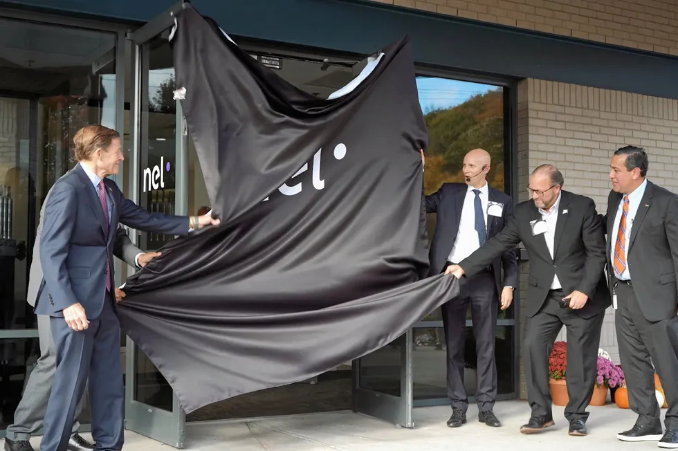Senator Richard Blumenthal, left, and Nel CEO Håkon Volldal, right with headset, along with colleagues, perform the 'curtain pull' that marked the official opening of the new facilities.