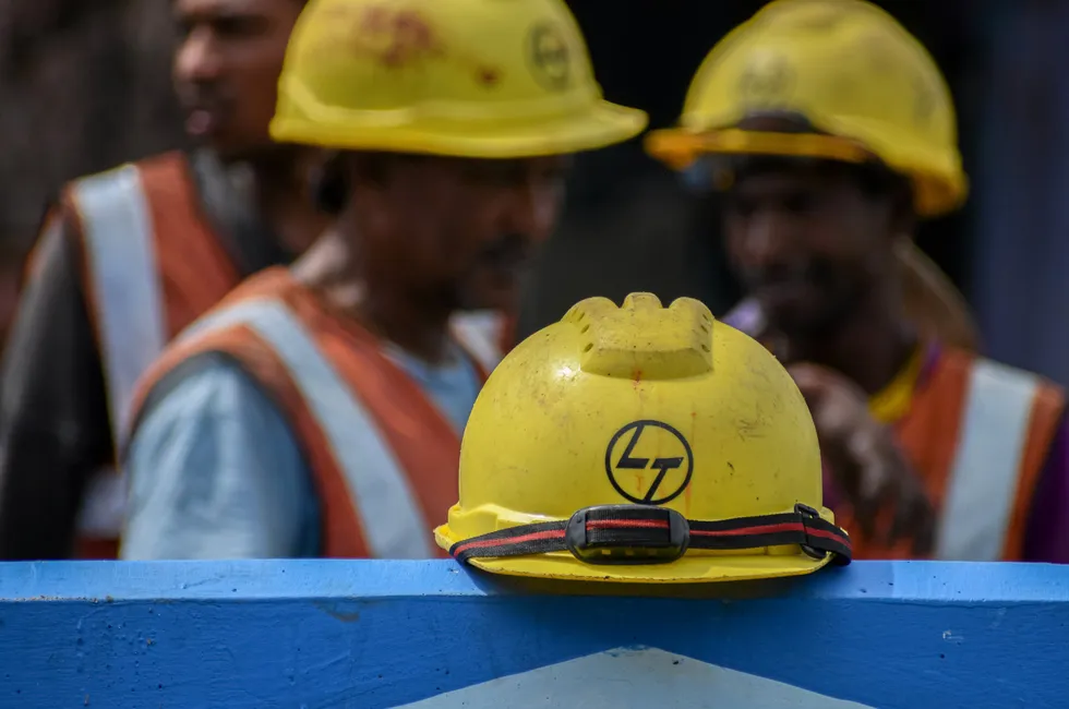 Safety helmets showing the L&T logo at a construction site in India.
