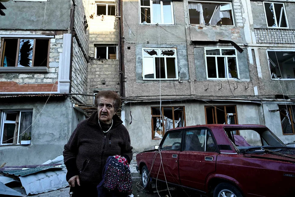 En eldre kvinne bærer sine eiendeler vekk fra leilighetskomplekset som er hardt rammet av kampene i byen Stepanakert i Nagorno-Karabakh.