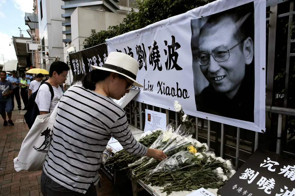 En kvinne legger ned blomster ved et bilde av Liu Xiaobo i Hongkong fredag. Foto: Kin Cheung, AP/NTB Scanpix