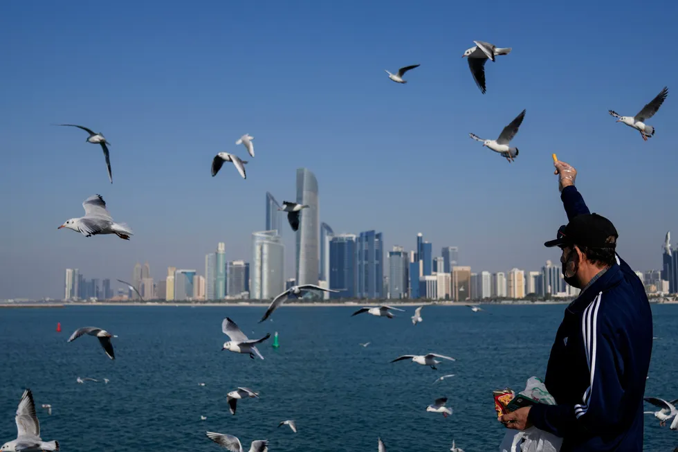With the city skyline in the background, a man feeds seagulls in Abu Dhabi, United Arab Emirates.