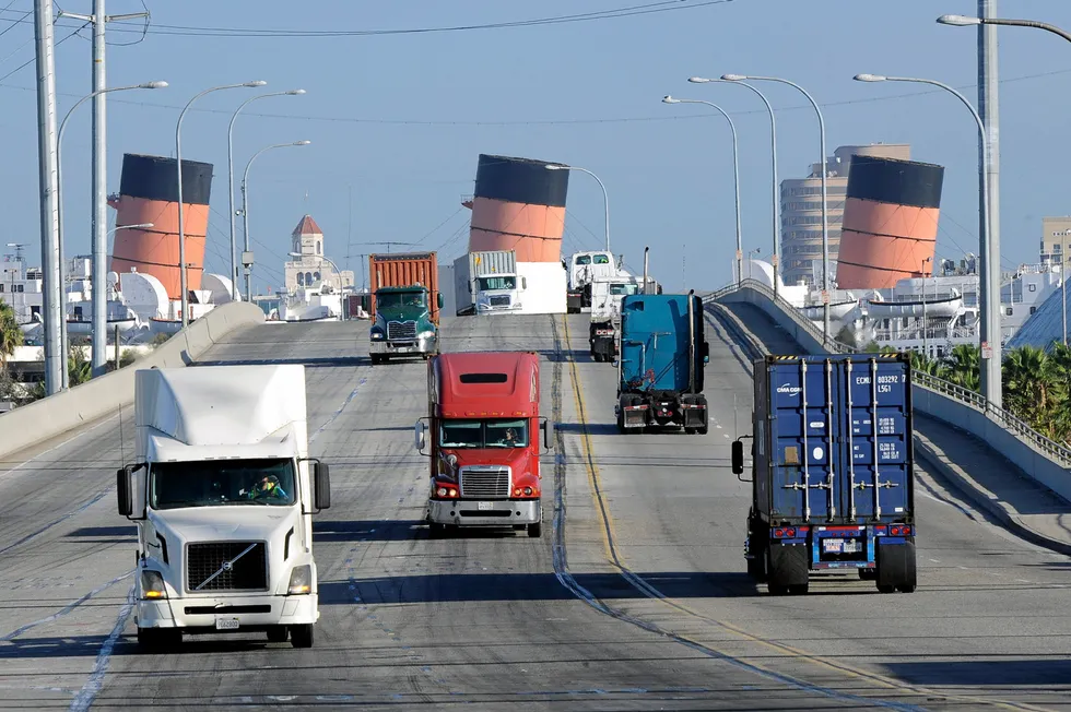 Trucks coming and going from the Port of Long Beach, California, with giant tilted ship funnels visible in the distance. It is these kinds of 'drayage' routes that are the most harmful to local residents, say officials.