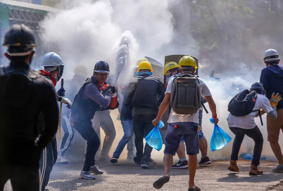 Friction: anti-coup protesters use fire extinguishers to reduce the impact of teargas fired by riot policemen in Yangon on 9 March