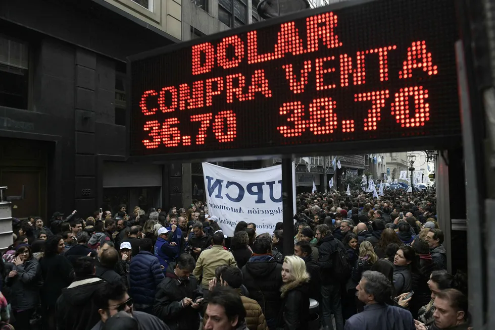 Statsansatte protesterer i Buenos Aires mot planlagte nedskjæringer og nedbemanninger, under et skilt som viser at valutaen peso har mistet halvparten av verdien mot dollar så langt i år.