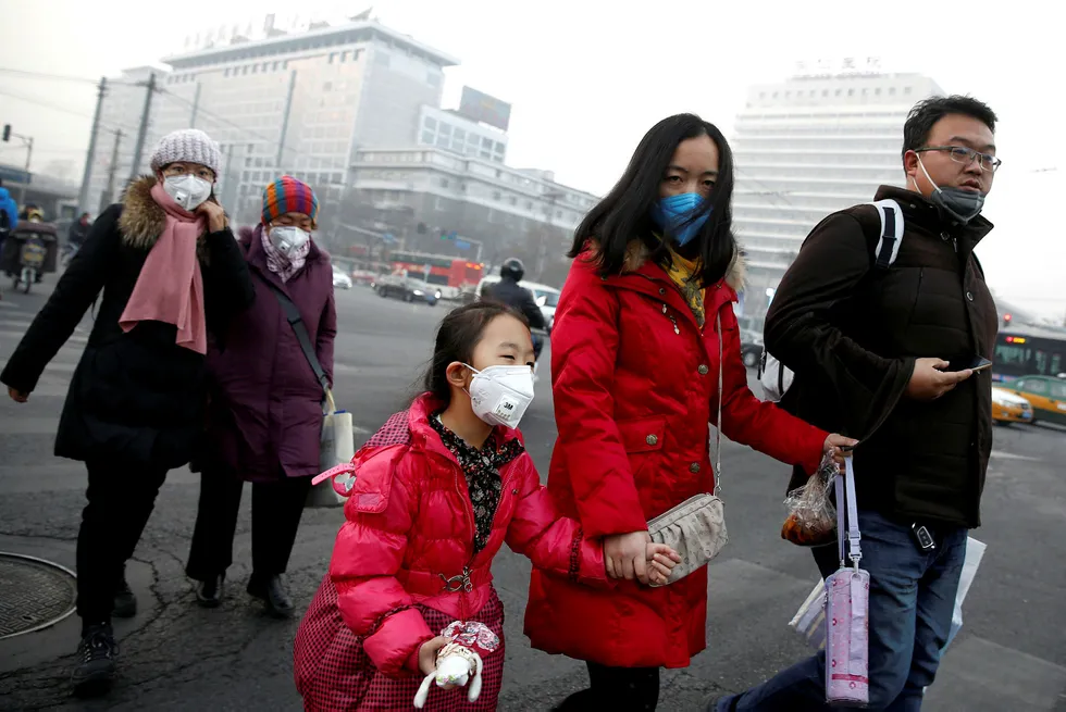 Folk er opprørt over luftforurensningen i Beijing og mange andre byer, og luftforurensningen er myndighetenes beste argument for lavere utslipp fra kullfyrte kraftverk, skriver artikkelforfatteren. Her en gruppe kinesere i Beijing, som bruker ansiktmaske. Foto: Thomas Peter/Reuters/NTB scanpix