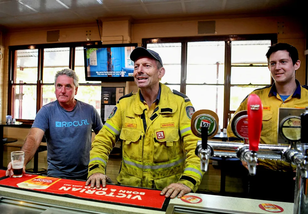 Australias tidligere statsminister Tony Abbott kjøper en runde øl til mannskapet sitt etter å ha kjempet som brannmann mot en skogbrann i New South Wales i januar. Nå er han utnevnt til britisk handelsrådgiver.