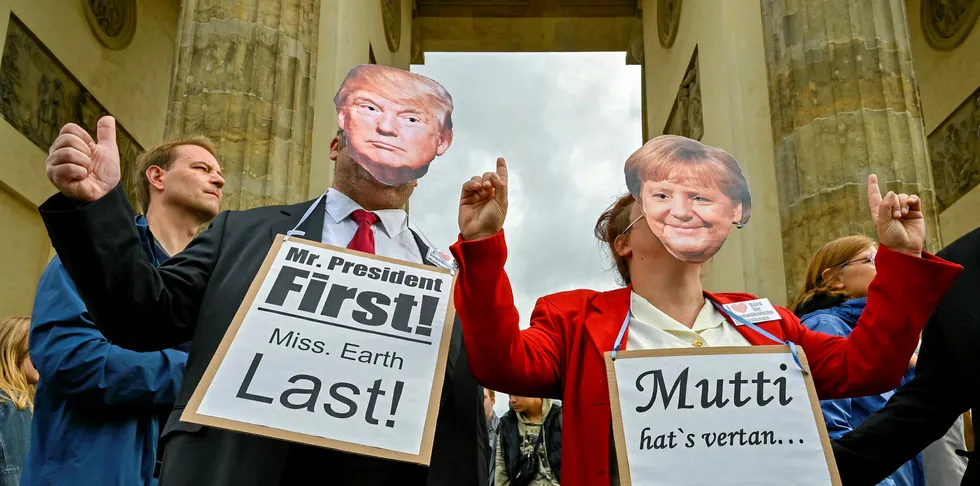 Two protesters wearing masks of US President Donald Trump and German Chancellor Angela Merkel hold signs reading "Mr President First, Mrs Earth Last" (L) and "Mutti (Mom, meaning Merkel) didn't make it, Youth must fix it" during the "Fridays for Future" demonstration at the Brandenburg Gate in Berlin during a protest for climate action on September 20, 2019, part of a global climate action day.