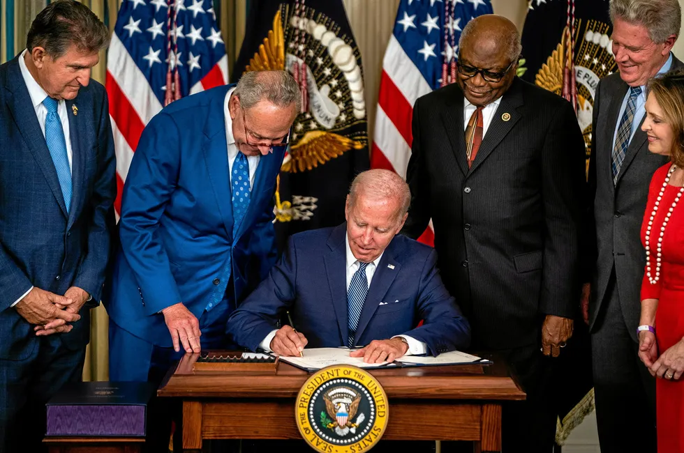 US President Joe Biden signs the Inflation Reduction Act of 2022 into law at the White House on August 16, watched by key lawmakers including the bill's authors, Senator Joe Manchin, left, and Senate Majority Leader Chuck Schumer, second left.