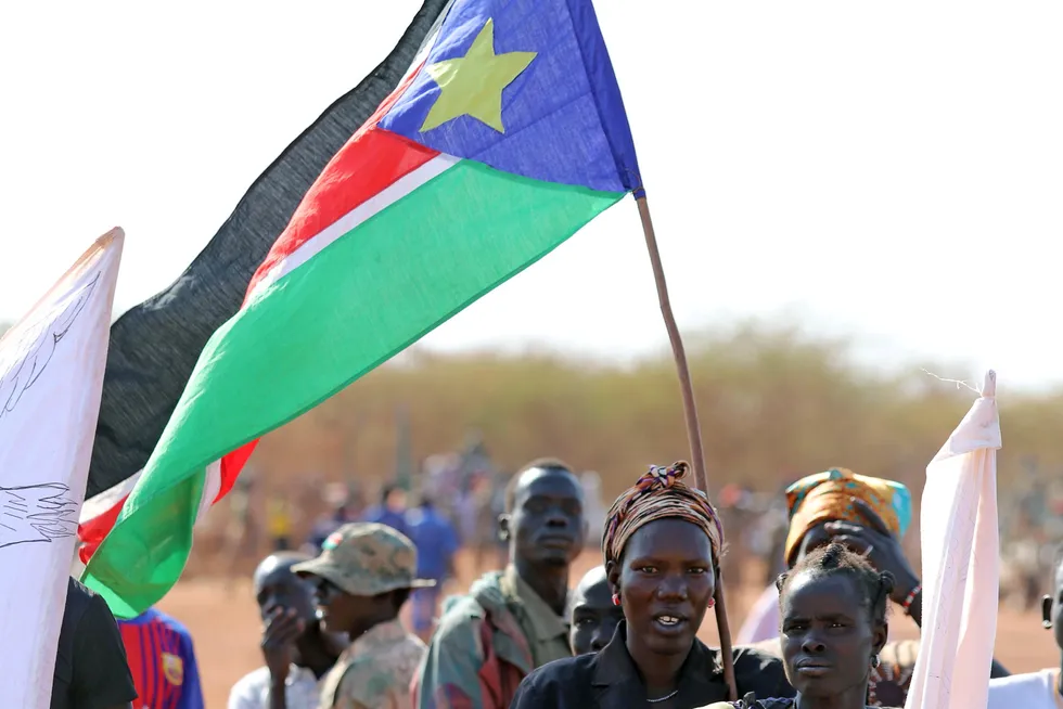 Women hold the South Sudanese flag during a ceremony marking the restarting of crude oil pumping at the Unity oilfields in South Sudan in January 2019.