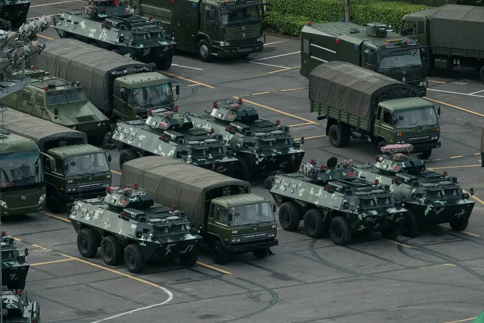 Trucks and armoured personnel carriers are seen parked at the Shenzhen Bay stadium in Shenzhen, bordering Hong Kong in China's southern Guangdong province, on August 16, 2019. - Chinese military personnel and armoured personnel carriers have mustered in large numbers across the border in Shenzhen, as Hong Kong's pro-democracy movement faces a major test this weekend as it tries to muster another huge crowd following criticism over a recent violent airport protest and as Beijing ramps up its bellicose threats. (Photo by STR / AFP)