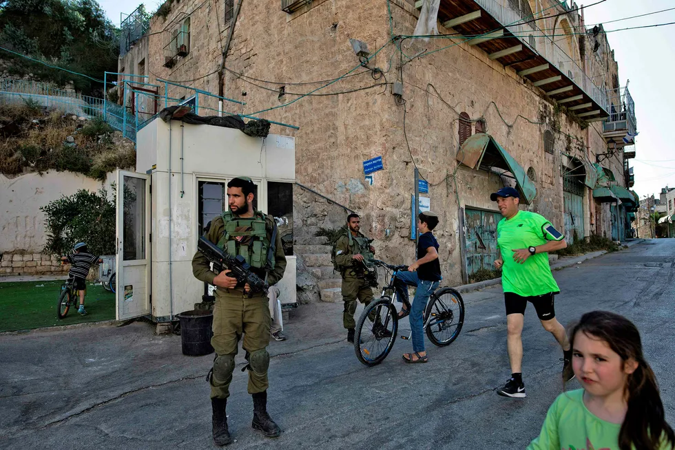 Israel har brutt mange FN-resolusjoner, men krav har aldri blitt sansksjonert. På bildet israelske soldater passer på en bosetting i den delte byen Hebron på Vestbanken. Foto: Menahem Kahana/Afp photo/NTB scanpix