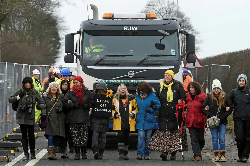 Anti-fracking protesters slow-walk in front of a gravel truck delivering at the Preston New Road site where Energy firm Cuadrilla are setting up fracking (hydraulic fracturing) operations at Little Plumpton near Blackpool in northwest England on January 10, 2017. Communities Secretary Sajid Javid gave the green light for the drilling of up to four wells by energy group Cuadrilla at the Preston New Road site in 2016, overruling a local council's decision to prevent the controversial scheme which is also opposed by environmentalists. Opponents fear that fracking -- a way of extracting gas by blasting water, chemicals and sand underground -- could pollute water supplies, scar the countryside, and trigger earthquakes. / AFP PHOTO / Paul ELLIS
