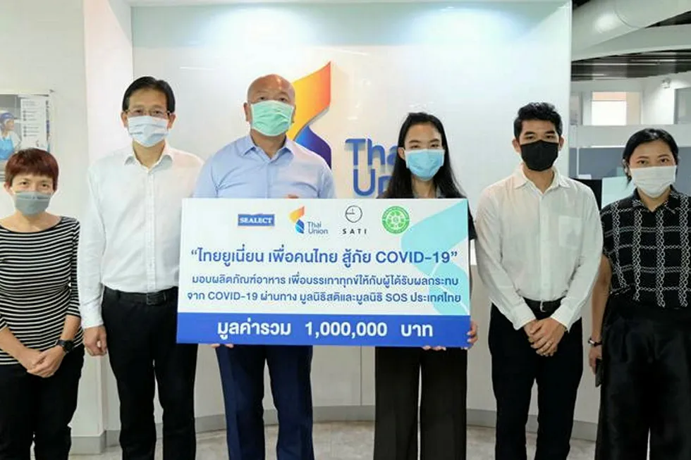Thiraphong Chansiri, CEO of Thai Union Group, stands with colleagues as they present a donation of tuna to Thai communities impacted by coronavirus.