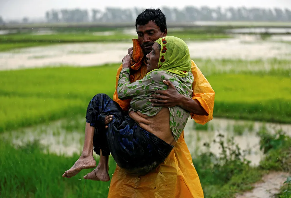 Conflict: a local man in Myanmar carries a Rohingya refugee woman