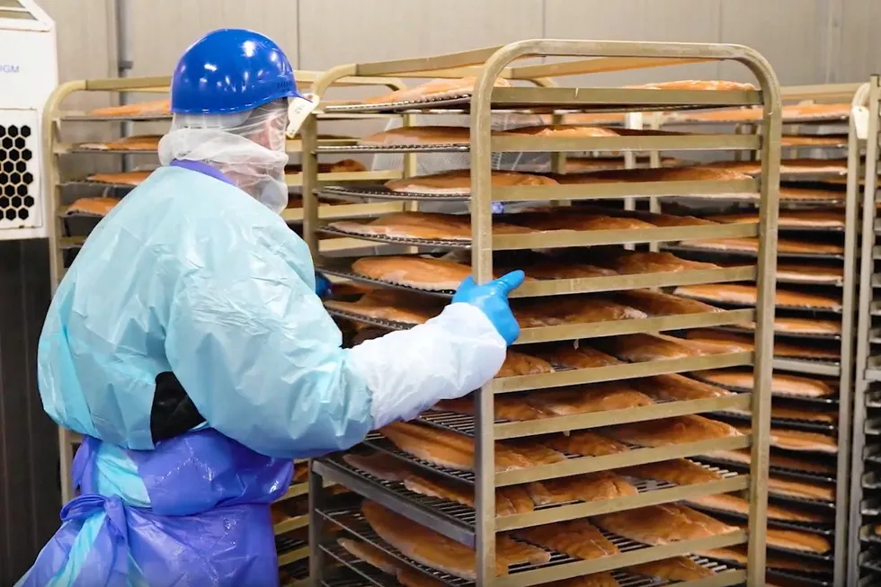 A worker at a Honey Smoked Fish Co. facility handles a tray of smoked salmon. The company announced it had sold off its Miami cold smoked salmon facility in early May.