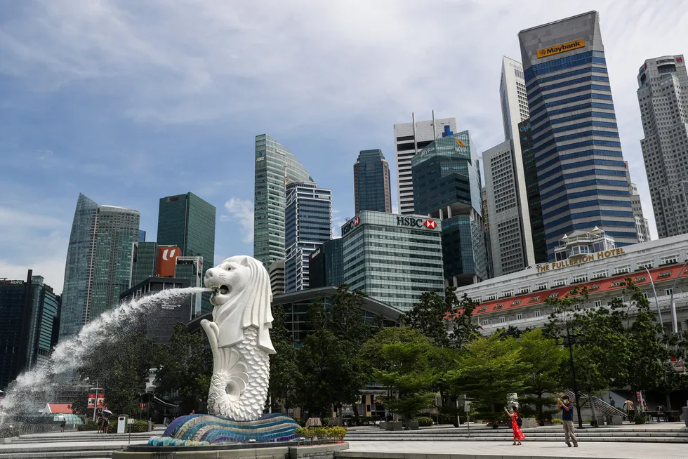 Central Business District: people are dwarfed against the financial skyline as they take photos of the Merlion statue along the Marina Bay area in Singapore