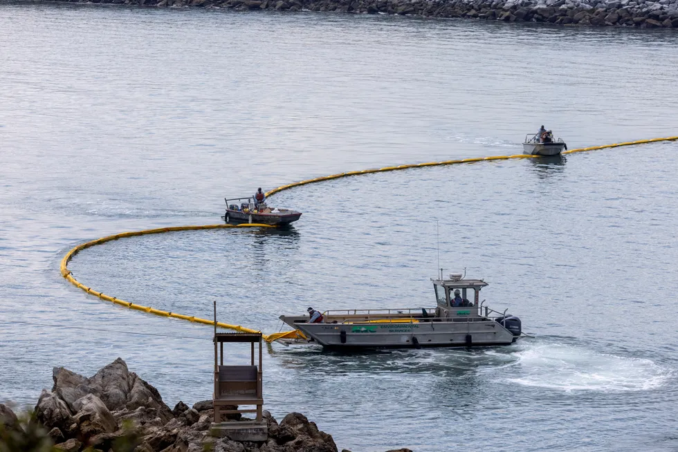 Cleaning up: Workers seal off the entrance to Newport Beach harbour as a major oil spill off the coast of California travels south in ocean currents, towards Newport Beach, California