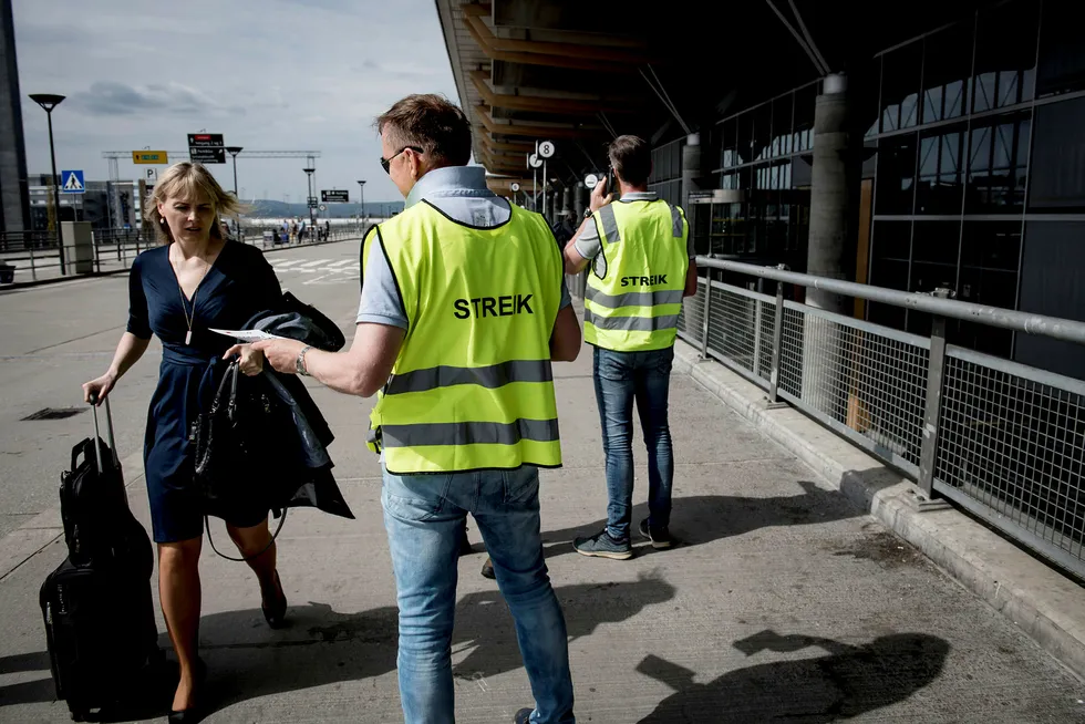 Streikevaktene Runar Østby (i midten) og Øystein Syrist (til høyre) deler ut løpesedler ved Oslo lufthavn Gardermoen tirsdag. Ingen av pilotene ville snakke med mediene.