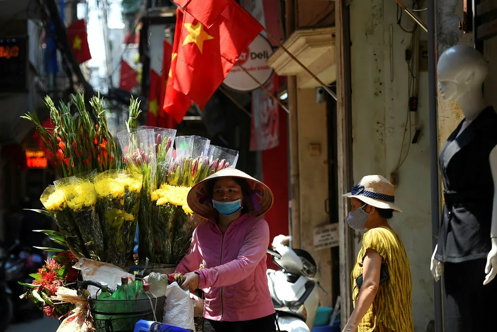 Downtown Hanoi: a street vendor passes through an alley way decorated with Vietnamese flags ahead of National Day celebrations on 1 September