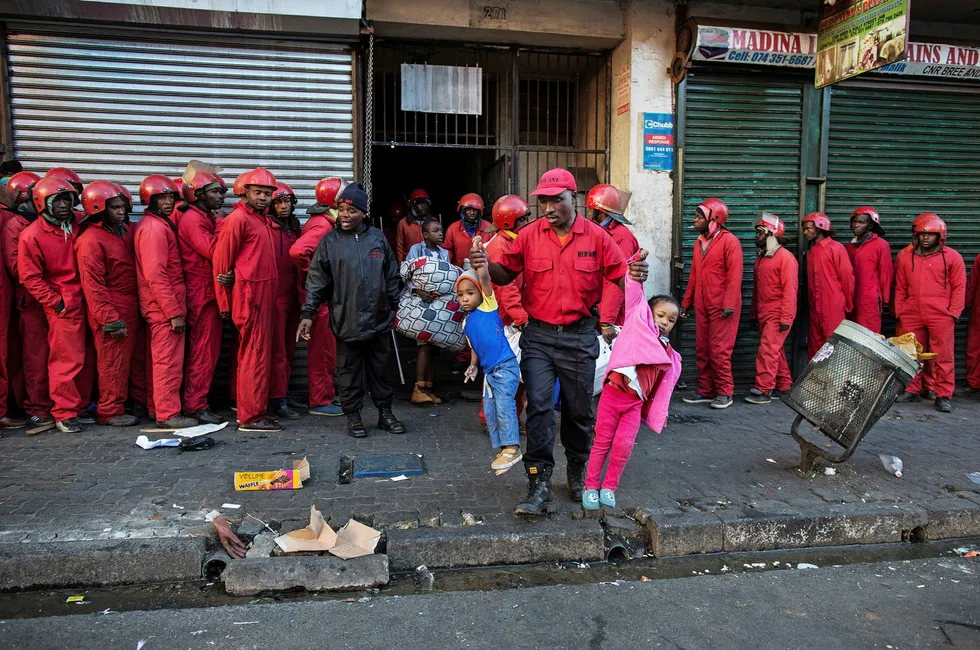Stort og smått. En leder i Red Ants bærer ut to småbarn under en masseutkastelse fra en såkalt «kapret gård» på Bree Street i Johannesburg. Øyenvitner sa at barna så ut som de nettopp var blitt vekket.