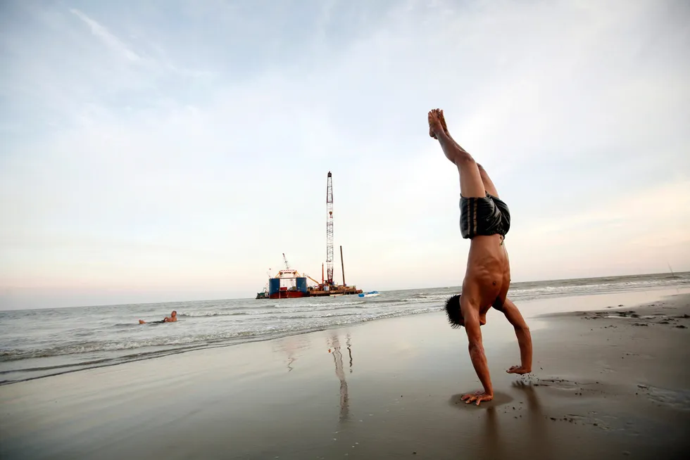 Myanmar infrastructure: a boy handstands on a beach as vessels involved in construction of the Yadana-Yangon subsea gas pipeline project are moored in the background