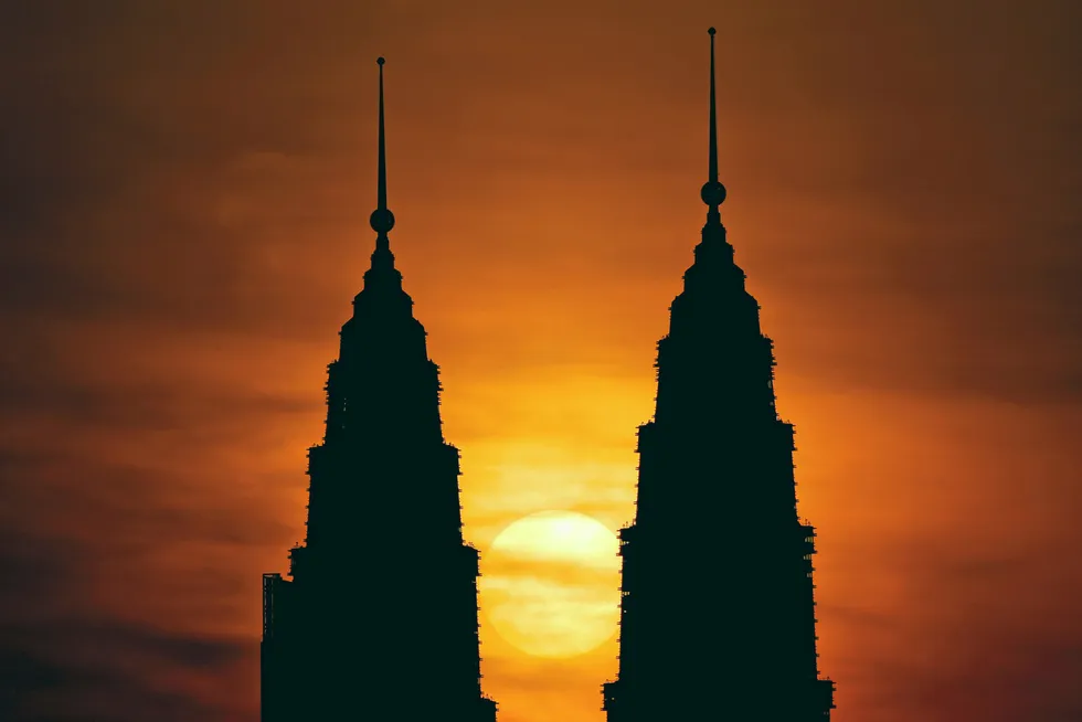 The sun rises behind Petronas Twin Towers in Kuala Lumpur, Malaysia
