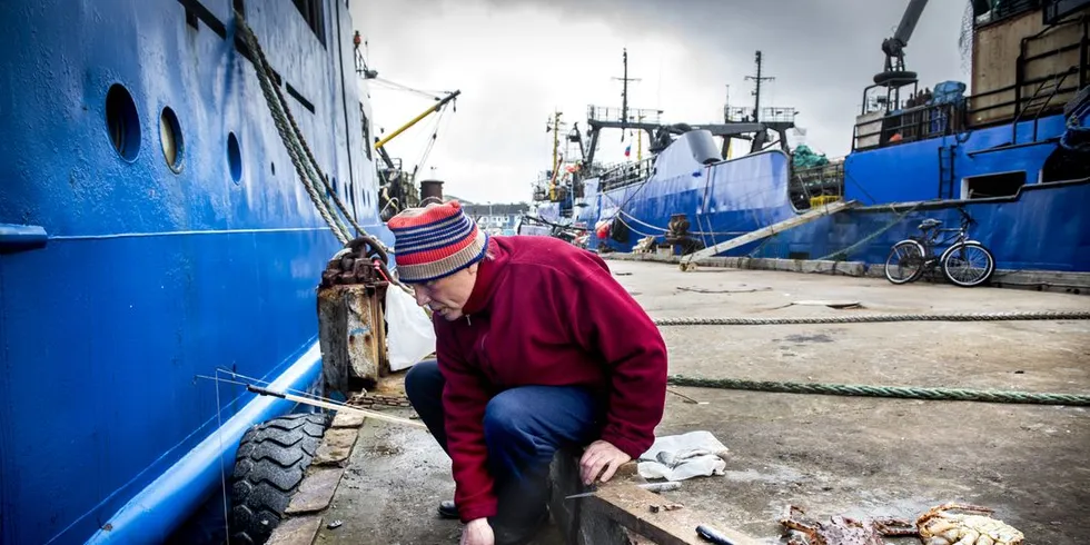 En russisk fisker sitter alene på brygga og fisker etter kongekrabber. Foto: Klaudia Lech