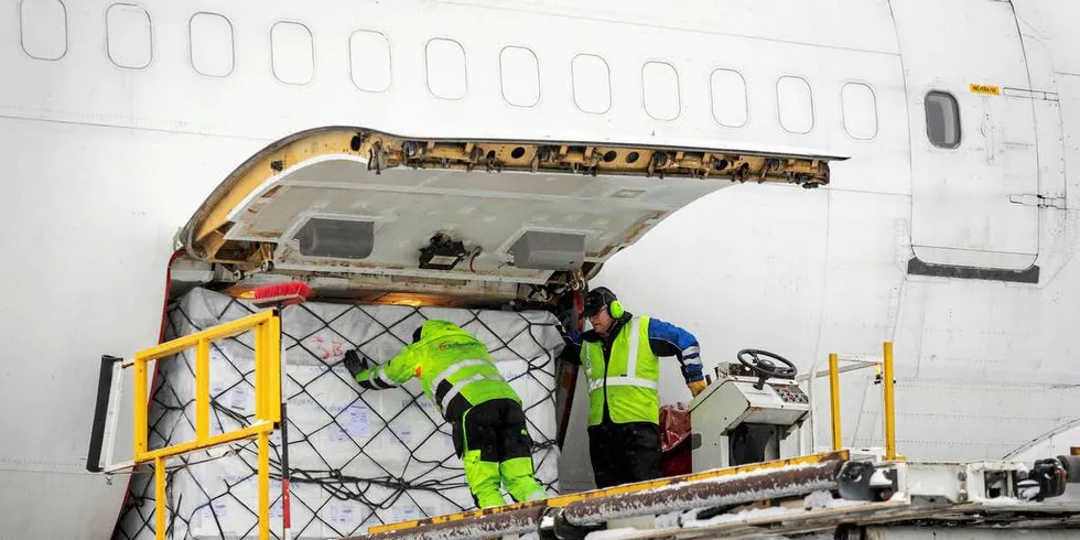 ØDELEGGENDE: Yngve Ramberg Skaug gir den siste av 14 paller med norsk laks et siste dytt inn i jumbojeten som skal fly til Kina. Vernon C.H. Thor (t.h.) styrer liften. Denne formen for fisketransport er ødeleggende for klimaavtrykket til norsk sjømat, mener Fiskeribladet på lederplassFoto: Gunnar Lier