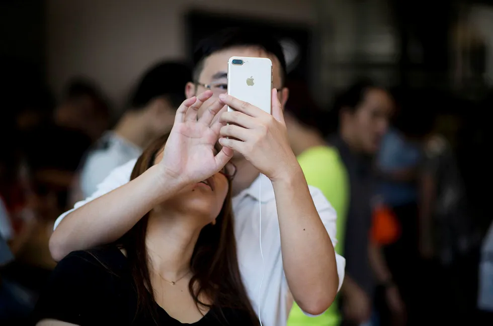 Apple er et av flere amerikanske selskaper som kan risikere tilbakeslag i Kina hvis Donald Trump innfører straffetoll mot landet. Her prøver et et kinesisk par Apples Iphone 7 i Shanghai i september. Foto: Johannes Eisele/AAP/NTB Scanpix