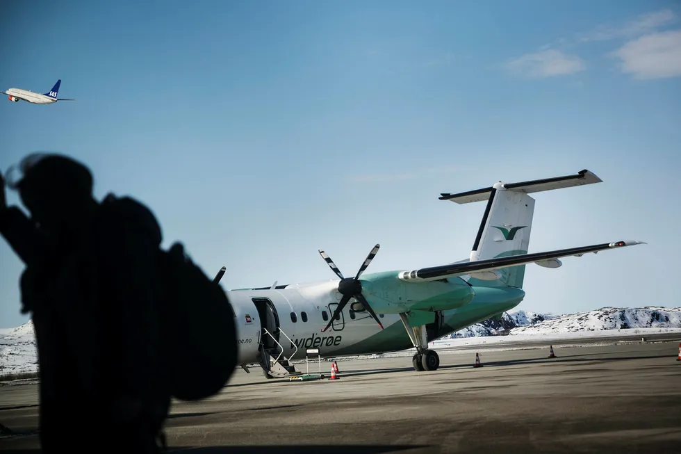 Et Widerøe- fly står her på Kirkenes lufthavn mens et SAS-fly tar av. Foto: Per Thrana