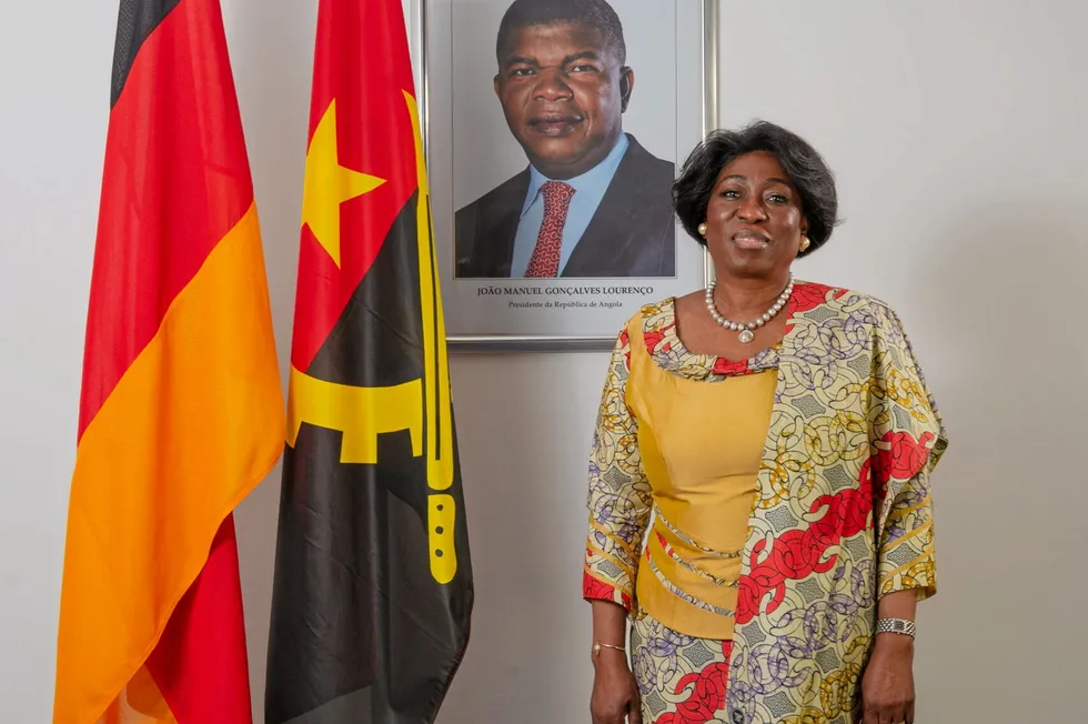 Angola's ambassador to Germany, Balbina da Silva, posing in front of a portrait of her country's president, João Lourenço.