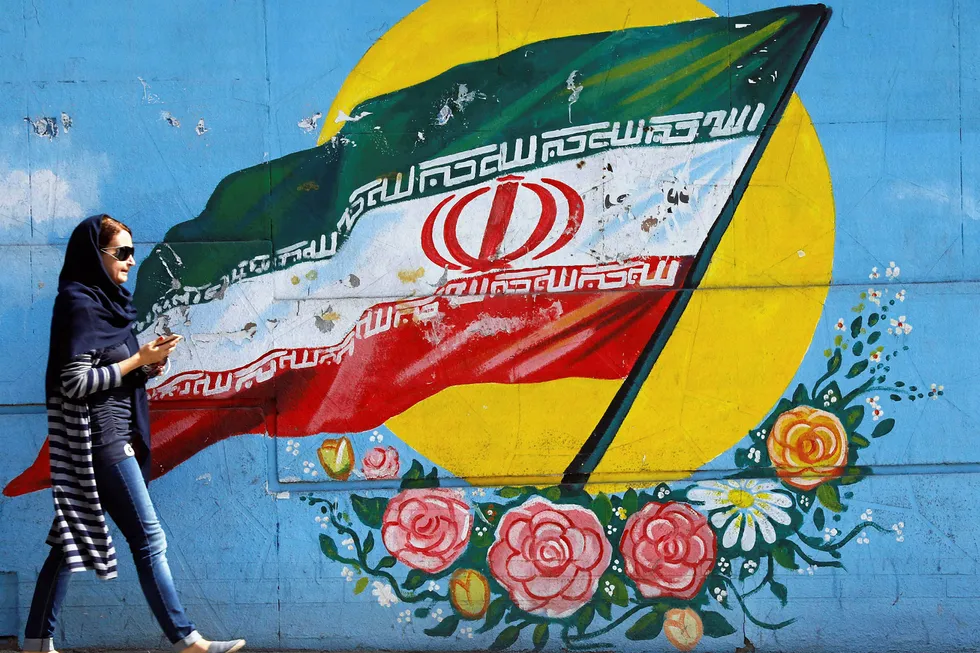 On the wall: an Iranian woman walks past a mural of the Iranian flag in the capital Tehran