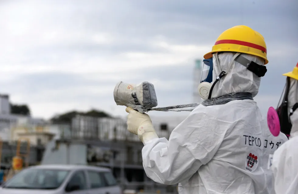 A Tokyo Electric Power Co. employee wearing a protective suit and a mask uses uses a survey meter at the Fukushima Dai-ichi nuclear power plant in 2013.