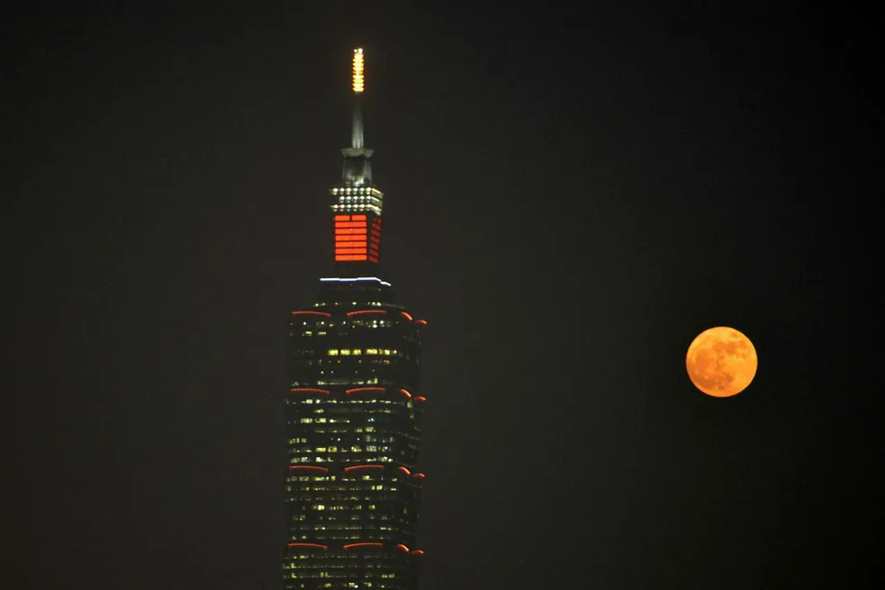 A 'supermoon' rises next to the Taipei 101 building, a 508-meter high skyscraper, in Taipei