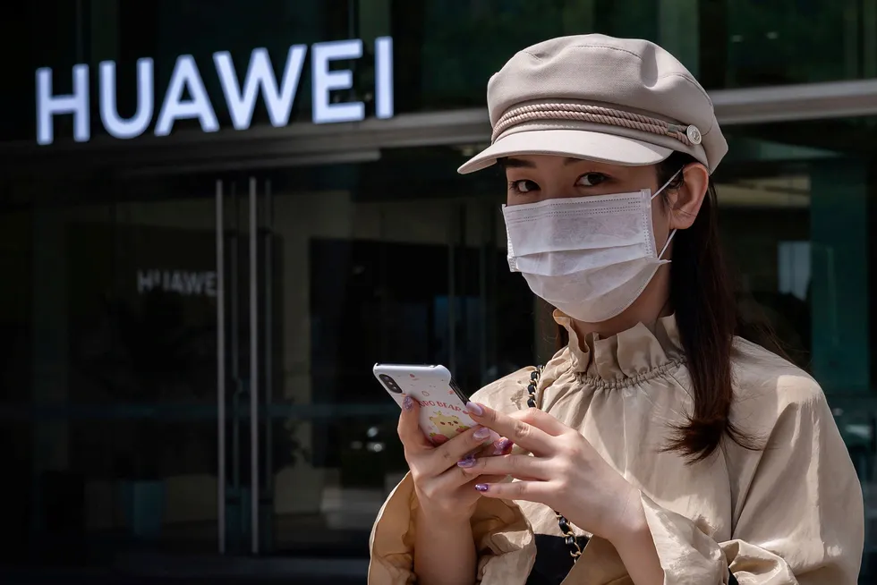 En kvinne går forbi en butikk tilhørende den kinesiske telekomgiganten Huawei i Beijing.