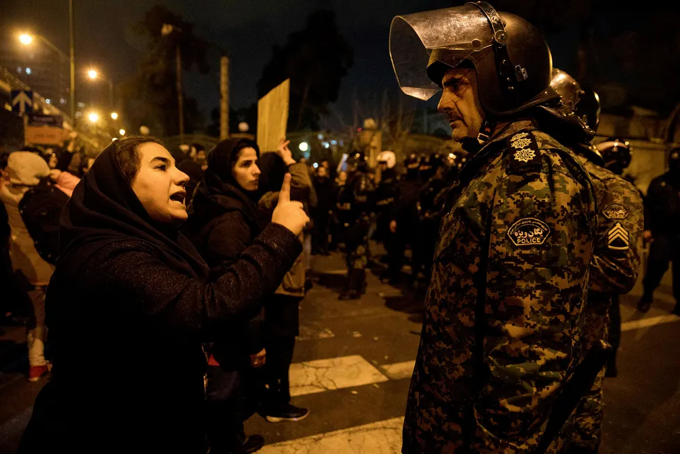 Regime under fire: a woman attending a candlelight vigil, in memory of the victims of Ukraine International Airlines Boeing 737, talks to a policeman following the gathering in front of the Amirkabir University in the Iranian capital Tehran