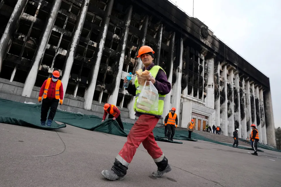 Clean-up task: municipal workers in the Kazakh city of Almaty prepare to cover the facade of the City Hall that was burned during mass unrest earlier in January, for repairs
